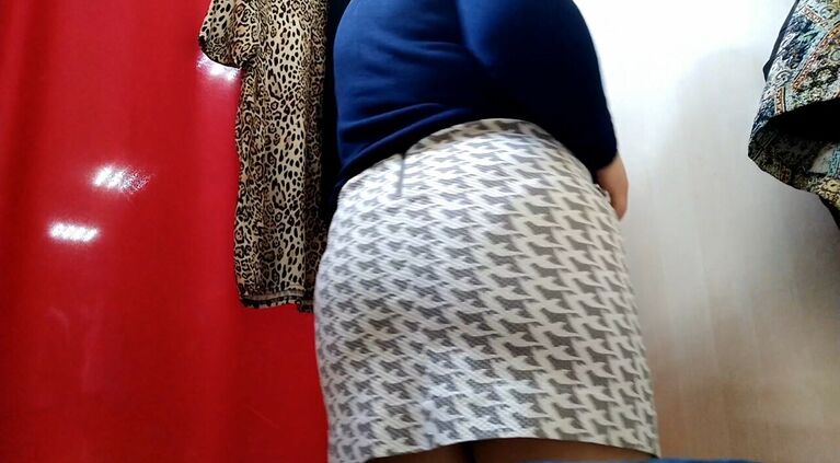 Curvy lady with a big butt tries on clothes in a shopping mall fitting room