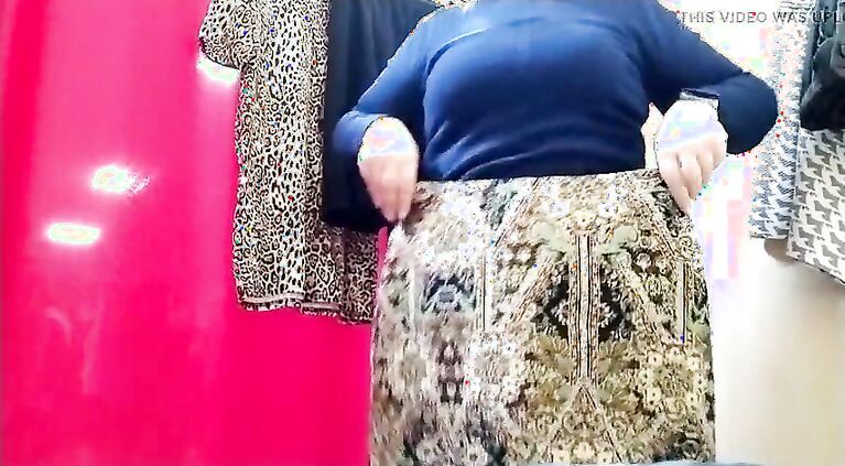 Curvy lady with a big butt tries on clothes in a shopping mall fitting room