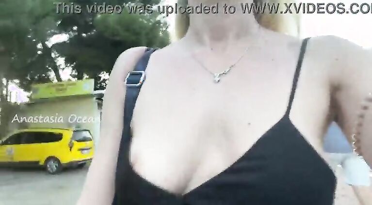 A hot girl walks around the city in a loose dress without underwear, shines her breasts in a public place.